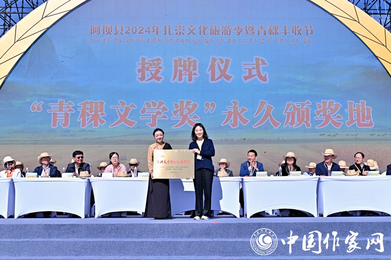 陳亞軍主編代表《民族文學(xué)》向阿壩縣授牌，紅梅部長接牌。